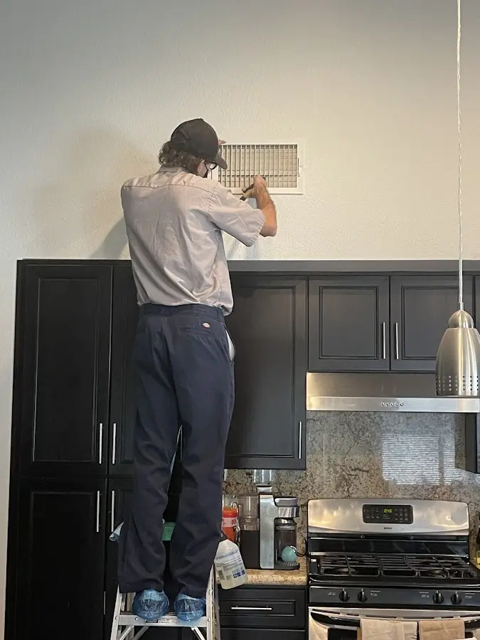 Technician inspecting an air vent during HVAC service in Allen